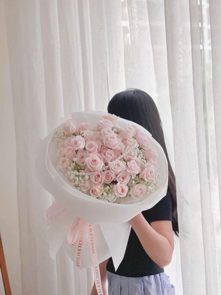 Bó hoa hồng phấn tinh tế kết hợp hoa baby trắng, được gói giấy sang trọng và ruy băng "LOVE IS ETERNAL", do STflowers thiết