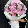 Bó hoa mẫu đơn hồng với những bông hoa tròn đầy, cánh hoa mềm mại, được gói trong giấy trắng và hồng, điểm xuyết lá xanh, tạ