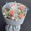 Bó hoa tươi thanh lịch với hoa hồng pastel, lily trắng và hoa điểm xuyết màu xanh biếc, gói trong giấy trắng tinh khôi, được