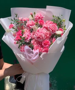 Bó hoa cẩm chướng hồng thắm được gói ghém tinh tế với giấy trắng, nơ hồng. Mẫu hoa đẹp từ STflowers Quận 7.