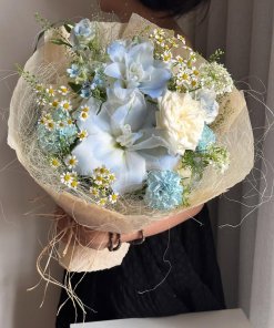 Bó hoa tươi với sắc xanh và trắng tinh tế, điểm xuyết cúc họa mi và lá xanh, được gói bằng giấy màu kem tự nhiên tại STflowe
