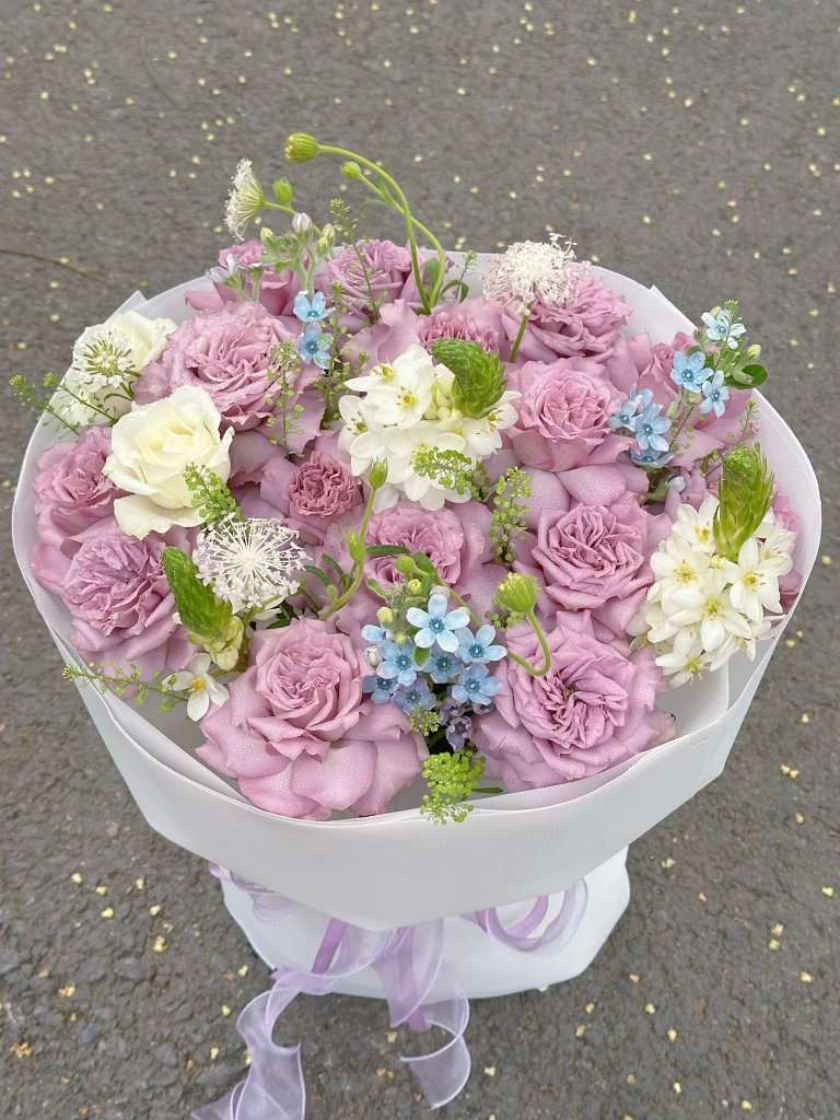 Bó hoa hồng tím lavender chủ đạo, kết hợp hoa trắng, xanh dương tinh tế, gói trắng sang trọng từ STflowers Quận 7.