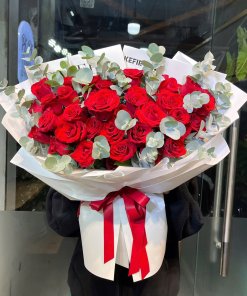 Bó hoa hồng đỏ rực rỡ gói giấy trắng tinh tế cùng lá eucalyptus xanh xám, quà tặng ý nghĩa từ STflowers tại TP.HCM. Thể hiện tình yêu nồng cháy.