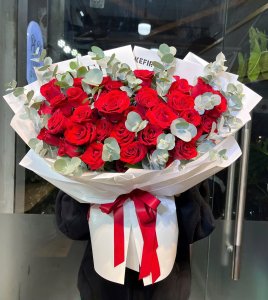 Bó hoa hồng đỏ rực rỡ gói giấy trắng tinh tế cùng lá eucalyptus xanh xám, quà tặng ý nghĩa từ STflowers tại TP.HCM. Thể hiện tình yêu nồng cháy.