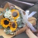 Bó hoa hướng dương tươi thắm kết hợp hoa baby trắng tinh khôi, gói giấy kraft nâu và nilon trong suốt, buộc nơ trắng sang trọng từ STflowers.