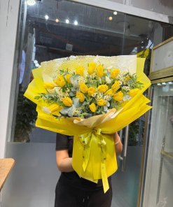 Bó hoa tulip vàng tươi rực rỡ với lá xanh và hoa baby trắng, gói giấy vàng sang trọng, STflowers giao tận nơi tại Quận 7, TP.HCM.