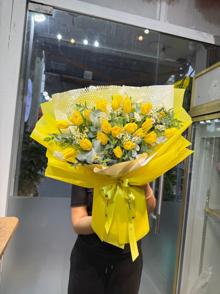 Bó hoa tulip vàng tươi rực rỡ với lá xanh và hoa baby trắng, gói giấy vàng sang trọng, STflowers giao tận nơi tại Quận 7, TP.HCM.