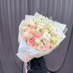 Bó hoa tươi tone hồng pastel và trắng, gói giấy sang trọng với nơ trắng lớn, trang trí ruy băng, của STflowers tại Quận 7, TP.HCM.