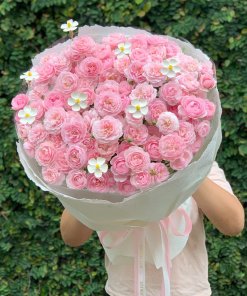 Một bó hoa hồng phấn lớn, thanh lịch được gói giấy trắng tinh tế, điểm xuyết hoa nhỏ trắng, đang được STflowers cung cấp tại TP.HCM.