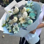 Bó hoa tốt nghiệp xanh trắng tươi tắn từ STflowers, với các bông hoa trắng đội mũ cử nhân và hoa tươi tone xanh dịu dàng.