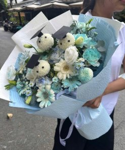 Bó hoa tốt nghiệp xanh trắng tươi tắn từ STflowers, với các bông hoa trắng đội mũ cử nhân và hoa tươi tone xanh dịu dàng.